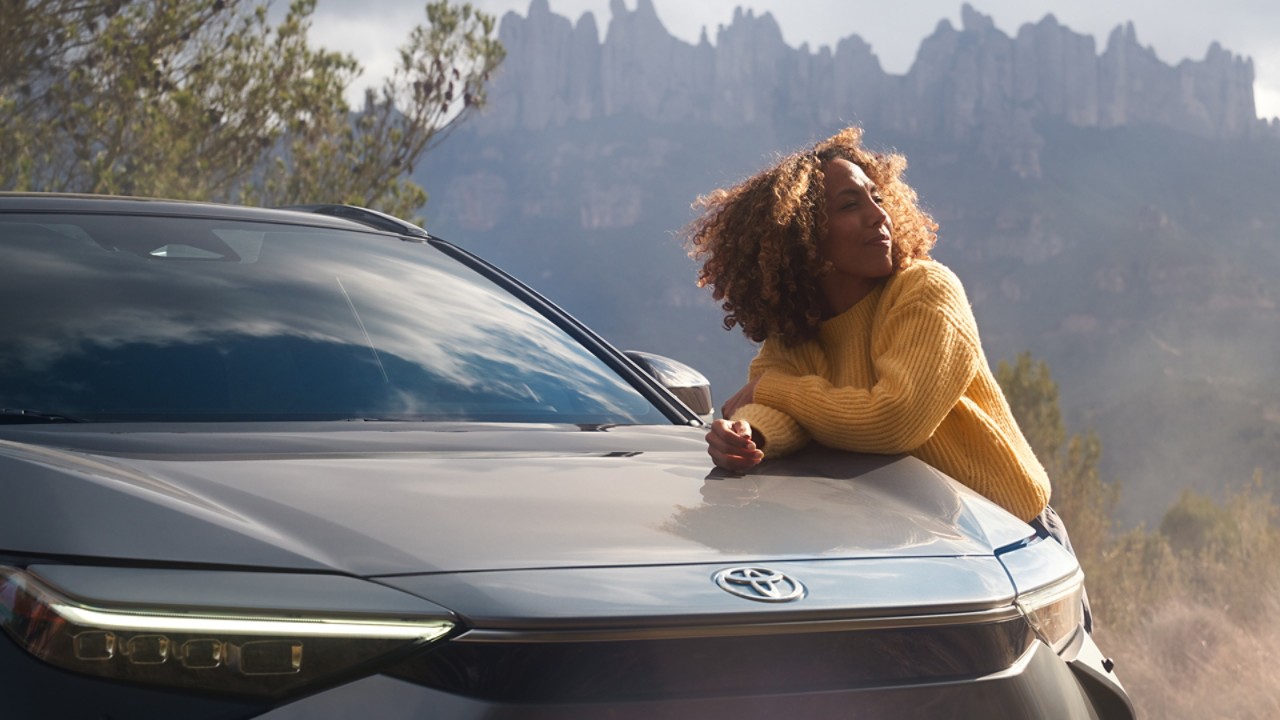 Relaxed young woman Toyota leaning on a Toyota